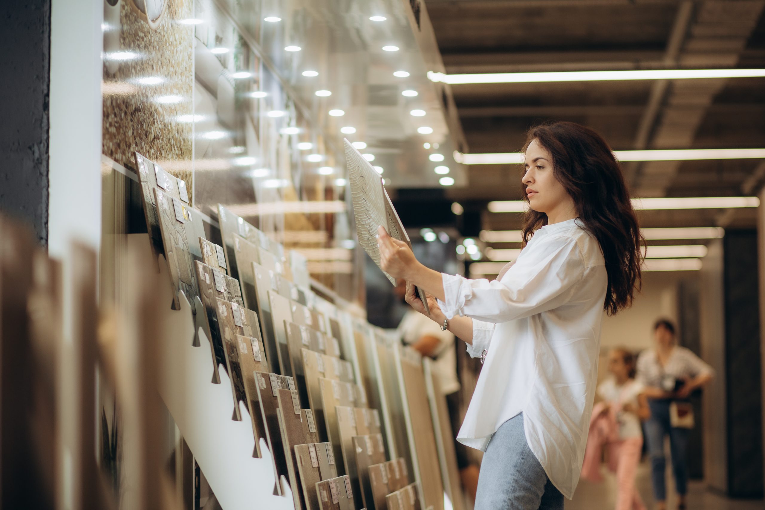 Jeune femme qui compare des carreaux de carrelage pour la rénovation de son intérieur.